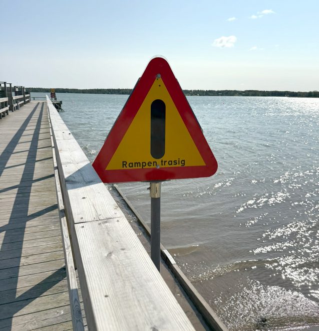 foto av varningsskylt vid brygga intill vatten