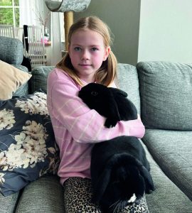 Foto av en flicka med en svart kanin i famnen