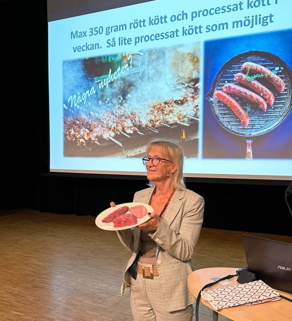 Foto visar kvinna framför skärm som håller upp tallrik med rått kött