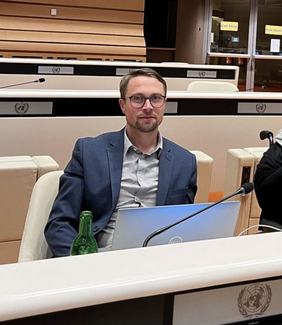 Foto visar nab med glasögon vid bord som har en FN-logga