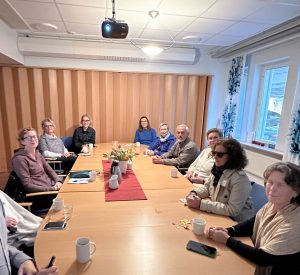 Foto visar personer runt ovalt träbord