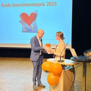 Foto visar kvinna som delar ut ett pris åt en man