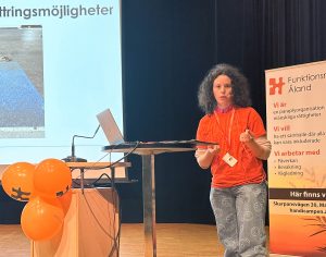 Foto av kvinna i orange t-shirt på scen