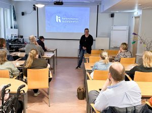 Foto visar publik bakifrån, länst fram föreläsare vid skärm