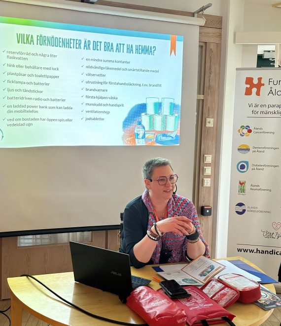 Foto av kvinna vid skrivbord, framför skärm med text