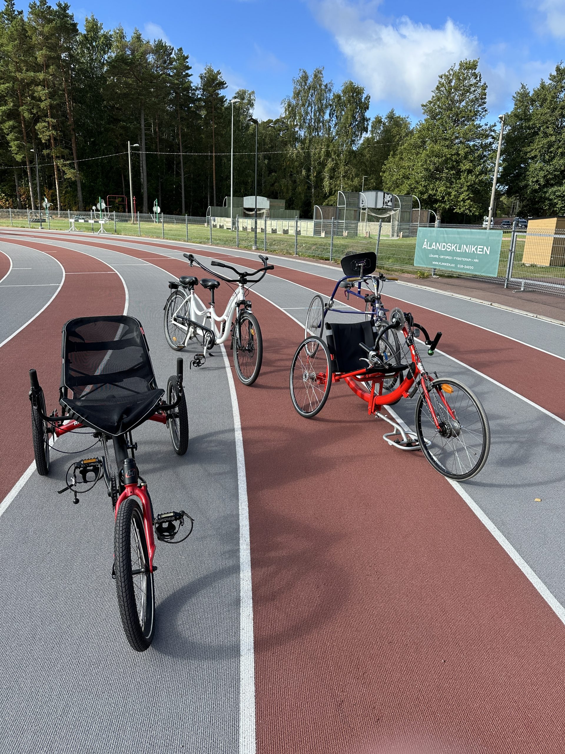 Foto visar tre cyklar, två trehjuliga och en tandemcykel