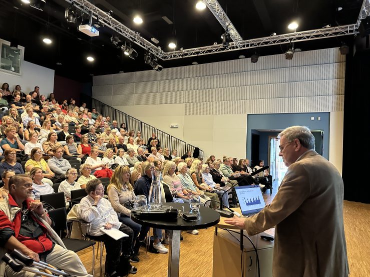Foto visar publik som ser på föreläsare vid dator